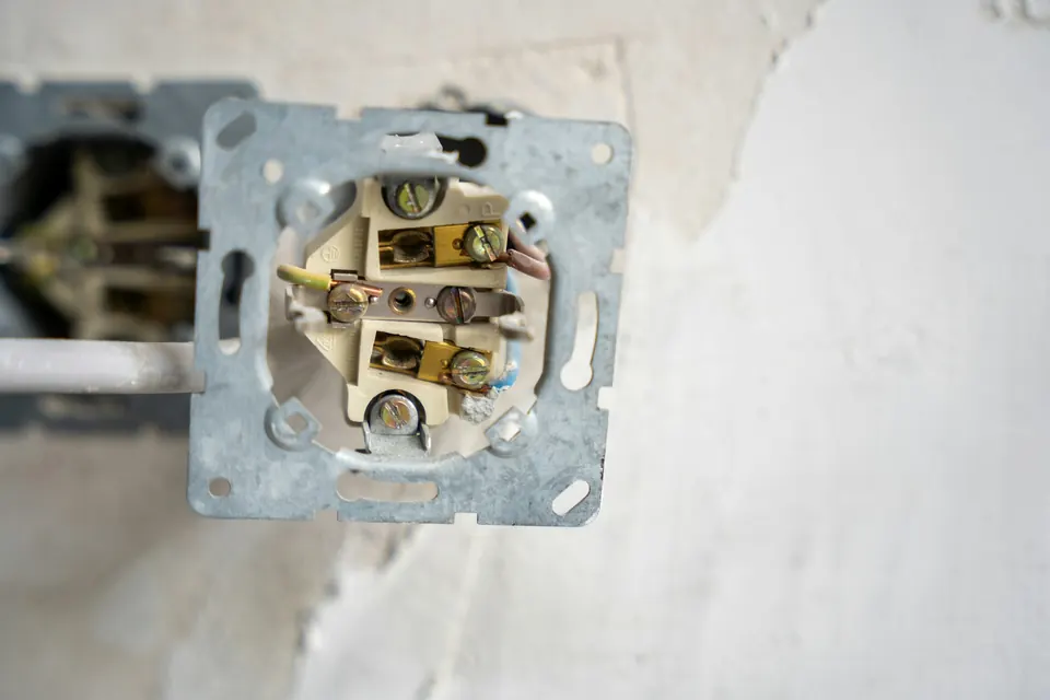Open inbouwdoos met een stopcontact in een gepleisterde muur