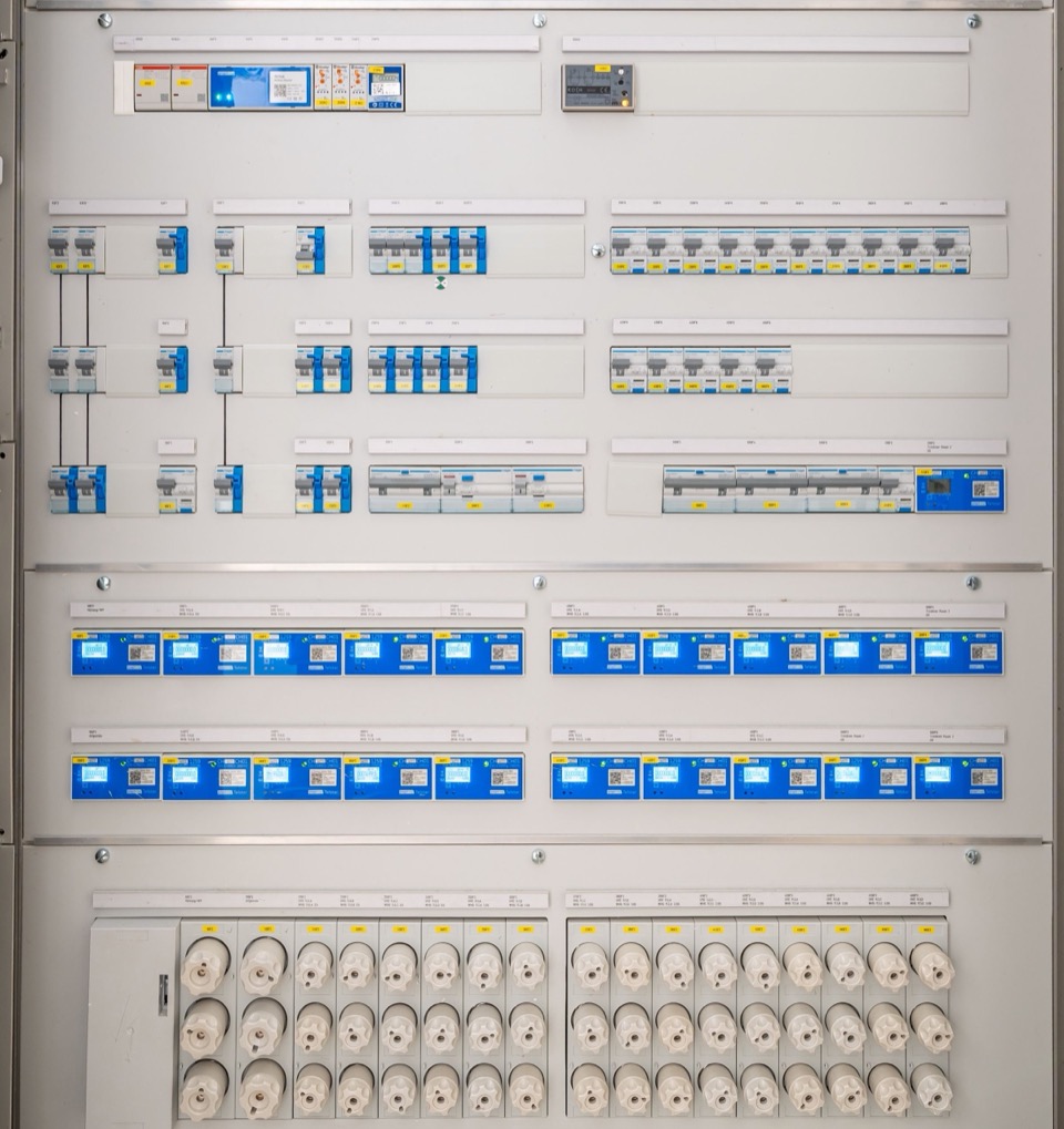 Een grote verdeelkast met rijen automaten en aardlekschakelaars in blauw en wit