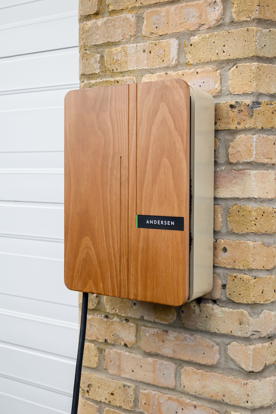 Een houten laadpaal aan een gele bakstenen gevel naast een witte garagedeur